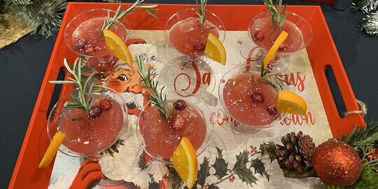 decorative drinks with an orange and rosemary sprig garnish on Santa tray at the zero proof mix off 