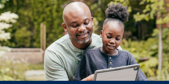 Father and daughter sitting together sharing one electronic tablet to schedule a vaccine appointment online