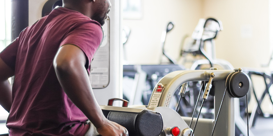 Adult seated on a workout machine to strengthen his arms. 