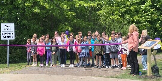 children standing in front of a sidewalk with a purple ribbon