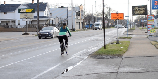 A woman with a brown ponytail biking down a city street