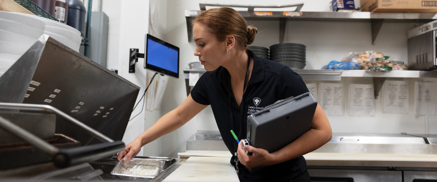 a woman with a clipboard does an inspection of a kitchen at a restaurant 