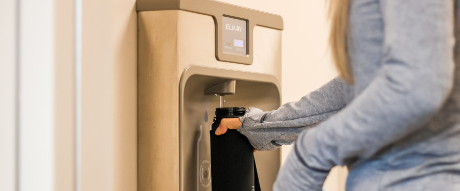 A woman fills up their water bottle at a hydration station 